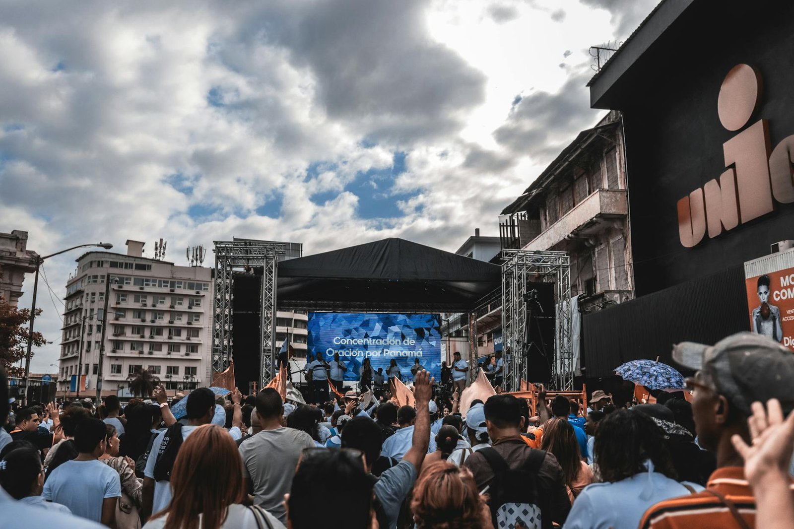 Large crowd gathered for a prayer event on an outdoor stage in the city.