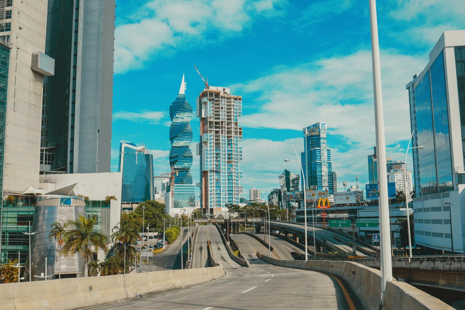 View of Panama City's skyline featuring modern architecture and empty highway under a bright blue sky.