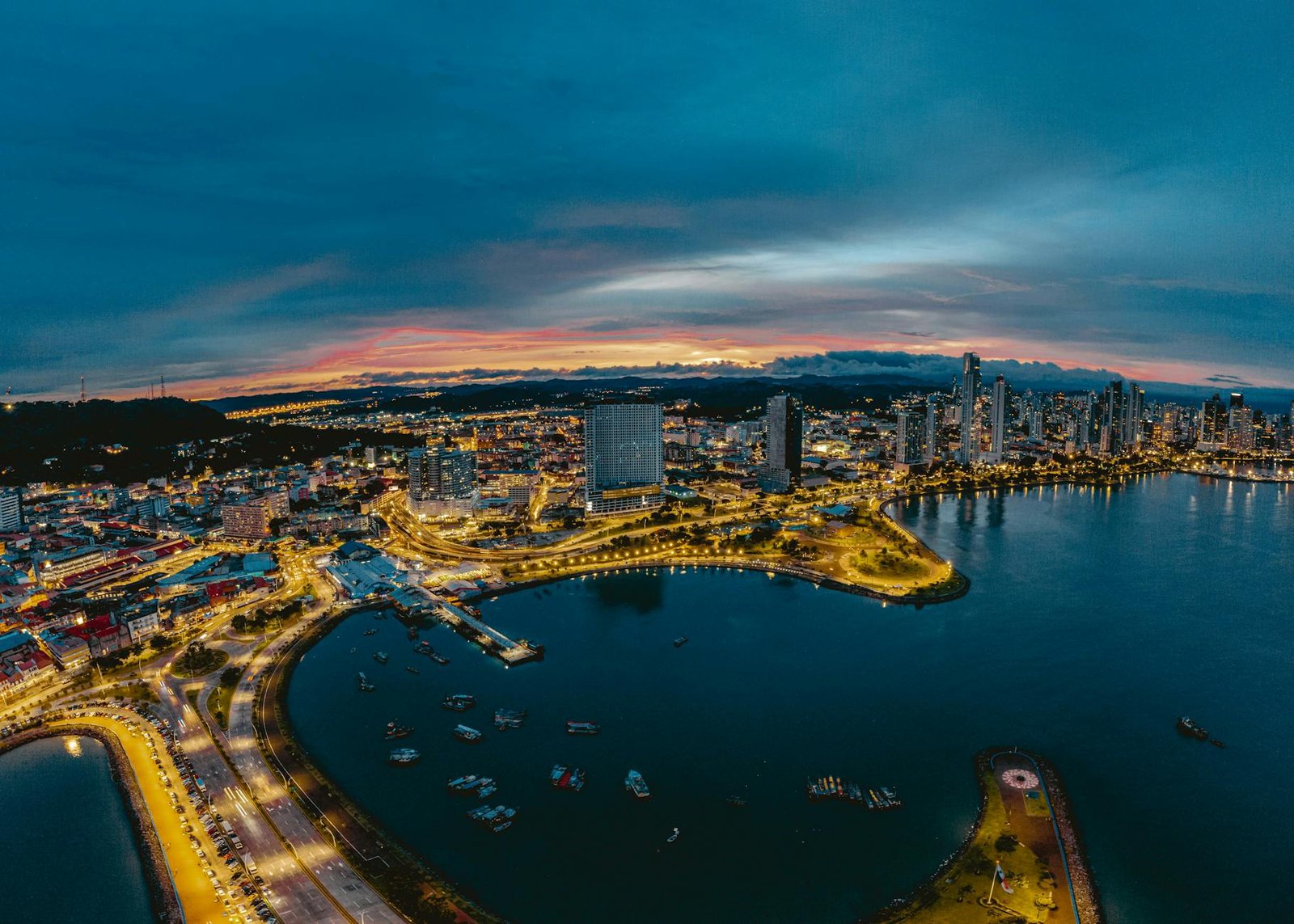 Stunning aerial view of Panama City's skyline illuminated at twilight over the ocean.