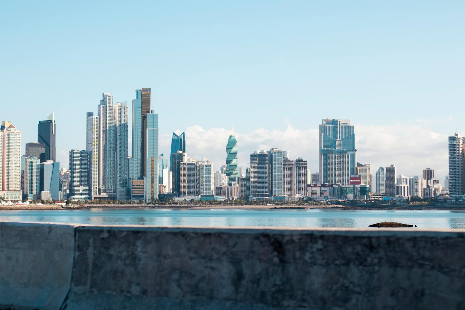Panama City skyline under clear blue sky, viewed from waterfront showing iconic skyscrapers.